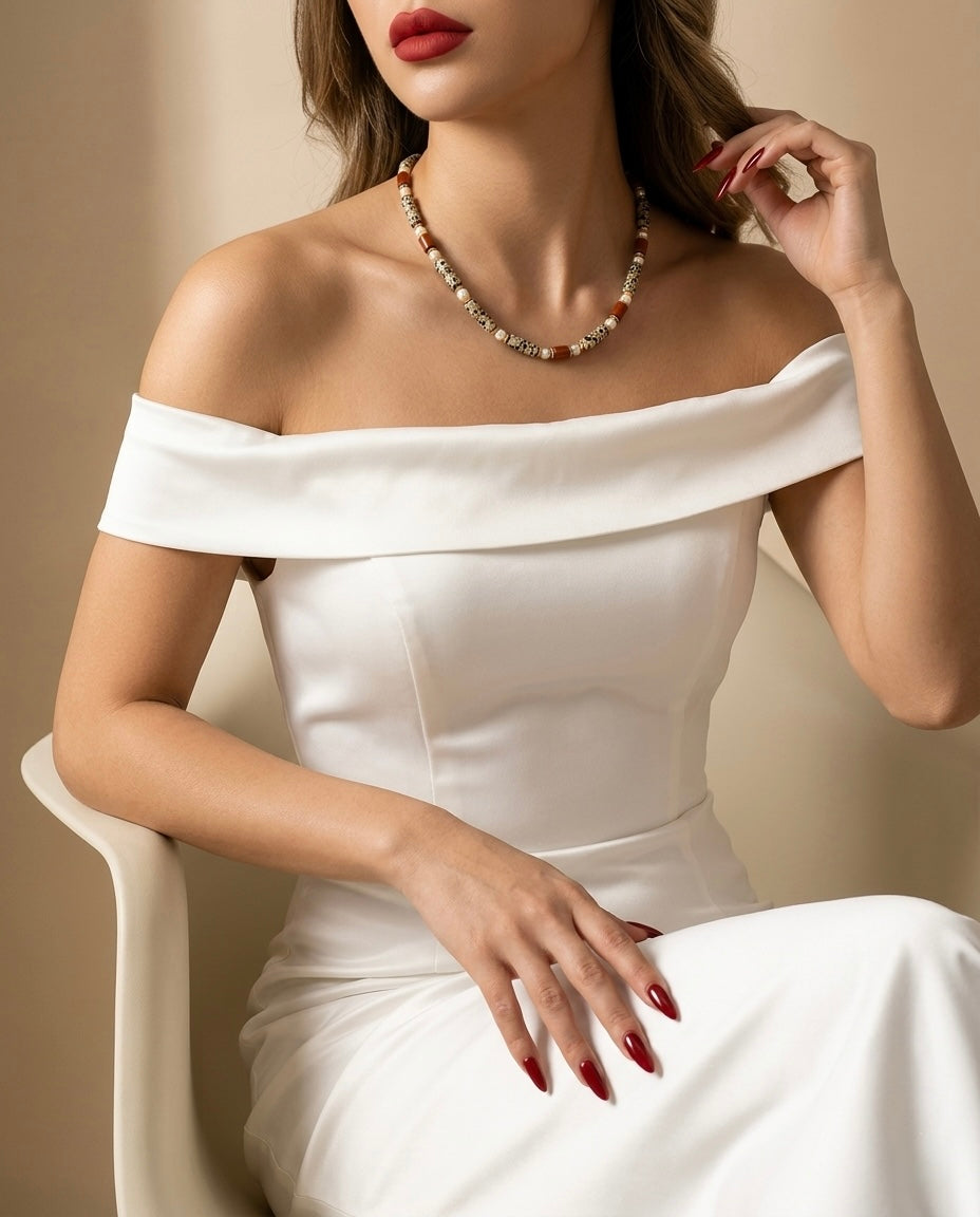 Woman wearing a white off-shoulder dress and pearl necklace against a beige background