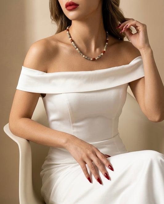 Woman wearing a white off-shoulder dress and pearl necklace against a beige background