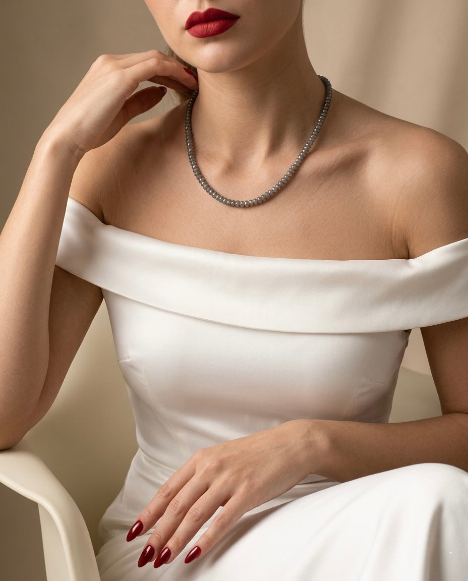 Woman wearing a white off-shoulder dress and a necklace with a neutral background