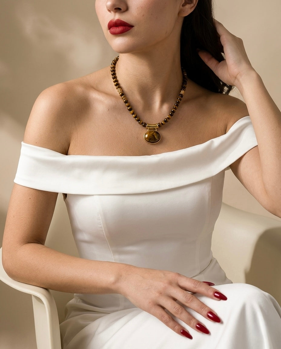 Woman wearing a white off-shoulder dress with a necklace against a beige background