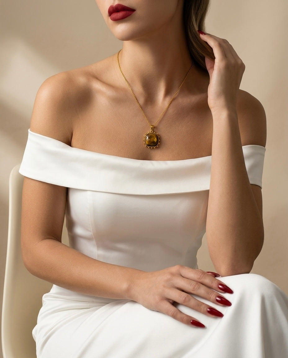 Woman wearing a white off-shoulder dress with a gold necklace against a beige background