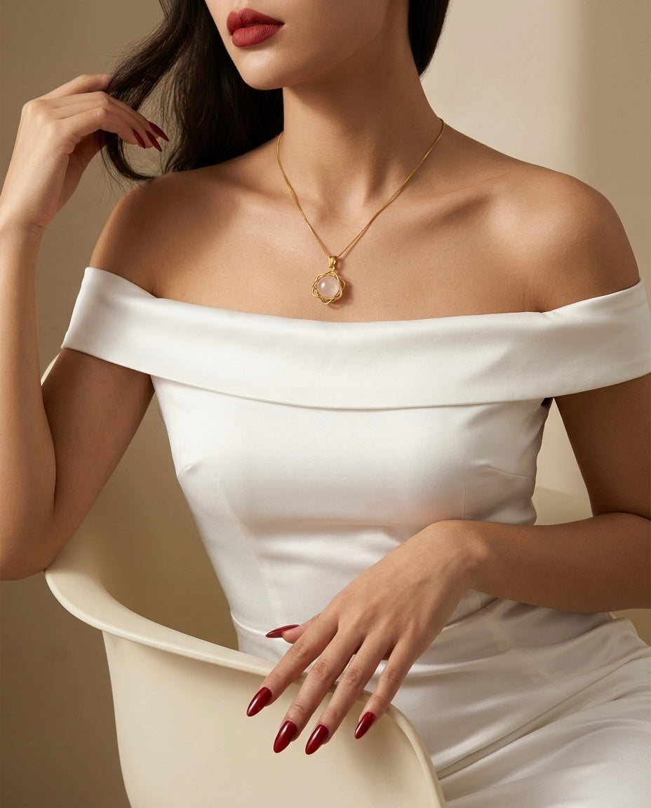 Woman wearing a white off-shoulder dress with a gold necklace featuring a pendant.