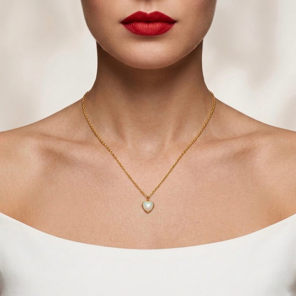 Gold necklace with a heart-shaped pendant worn by a model against a neutral background
