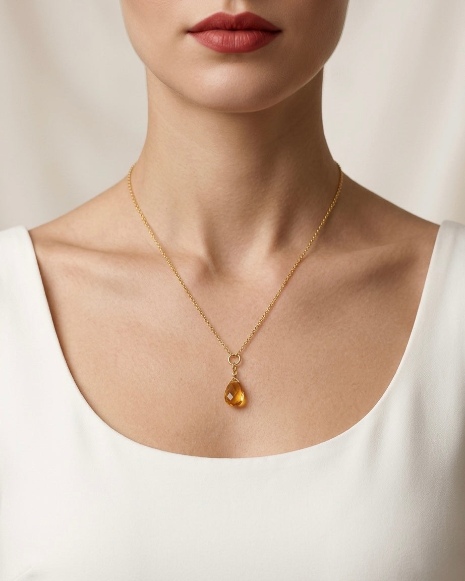 Gold necklace with a pendant worn by a person against a neutral background