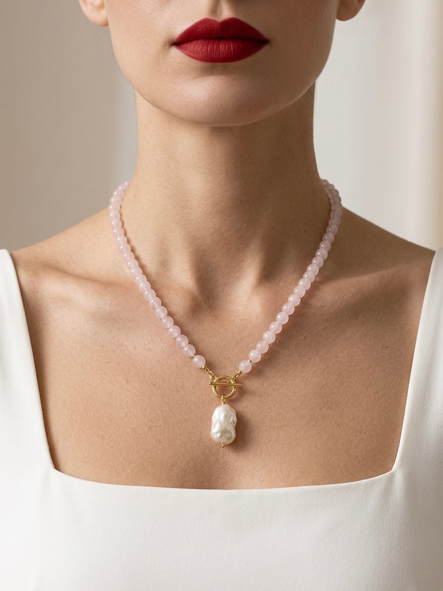 Necklace with a baroque pearl pendant worn by a person with red lipstick.