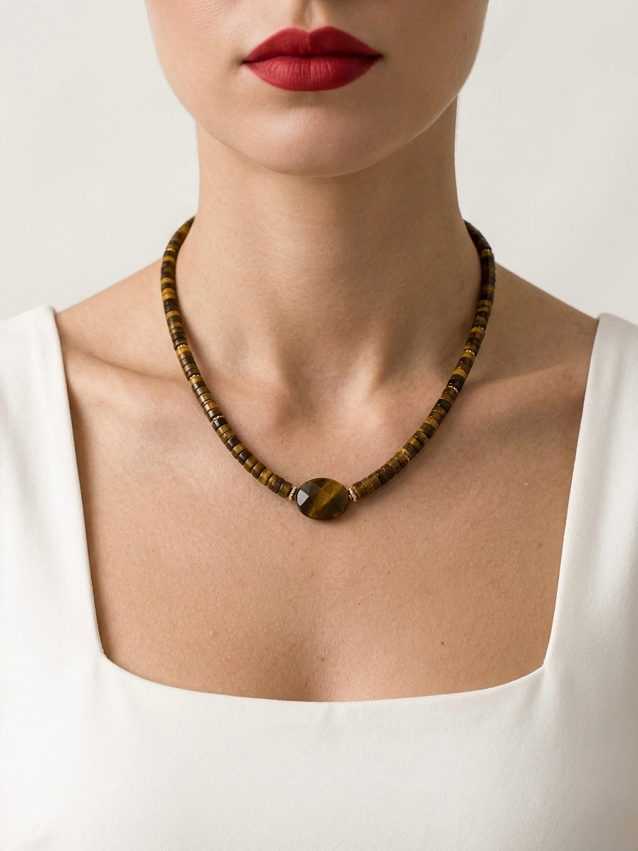 Necklace with a large brown bead worn by a person against a neutral background