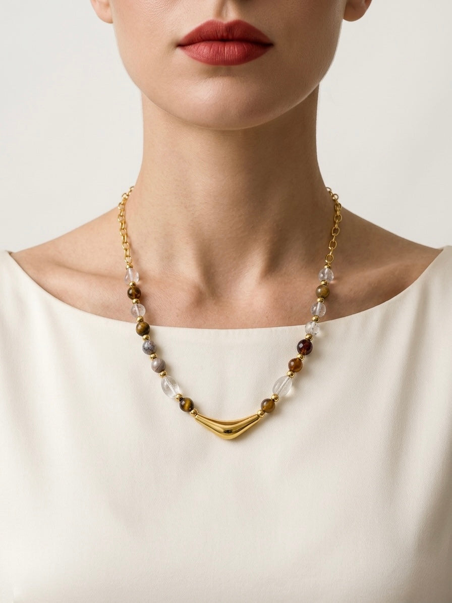 Necklace with beads and gold accents worn by a person against a neutral background