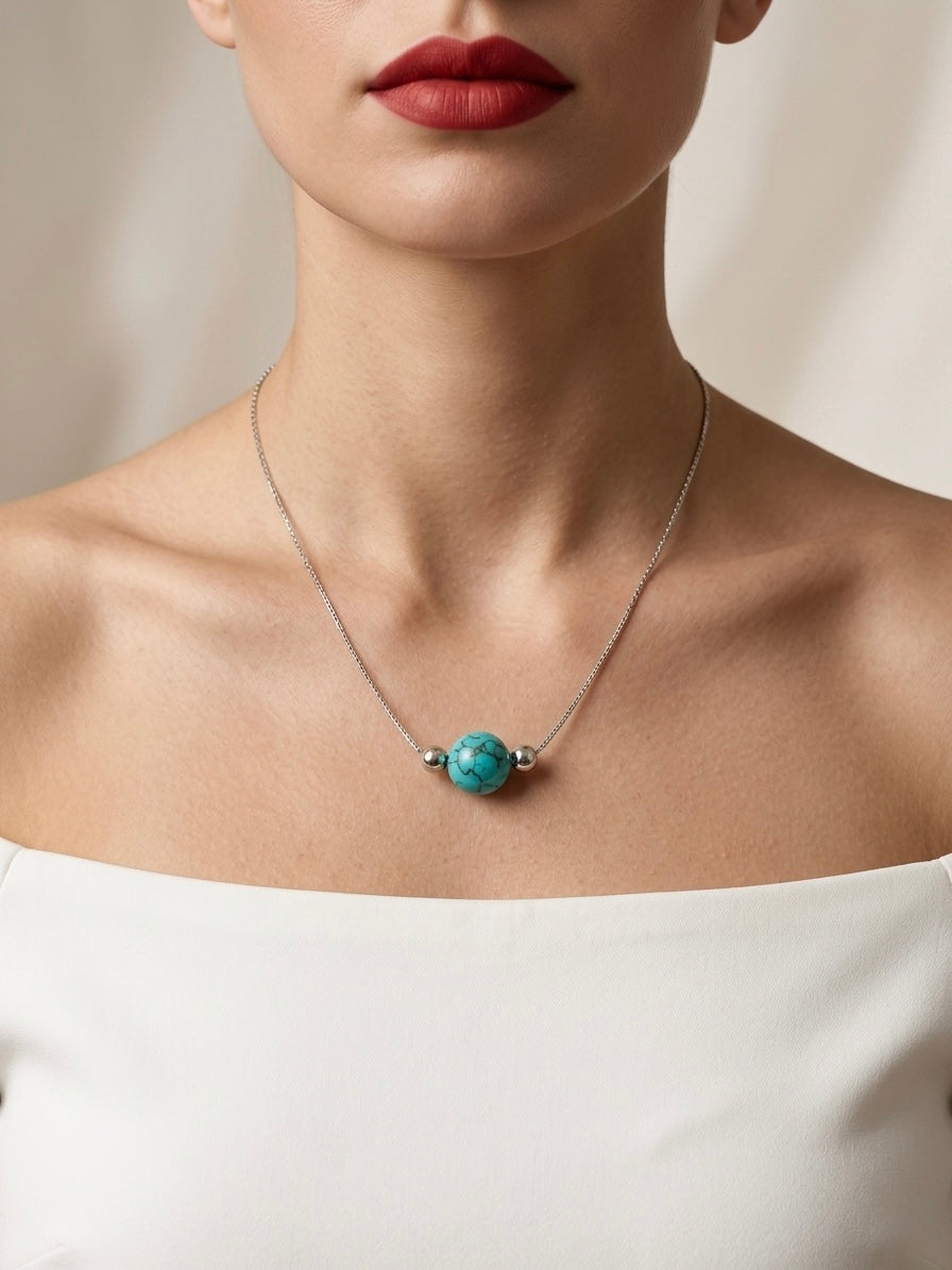 Necklace with a turquoise pendant worn by a person against a neutral background