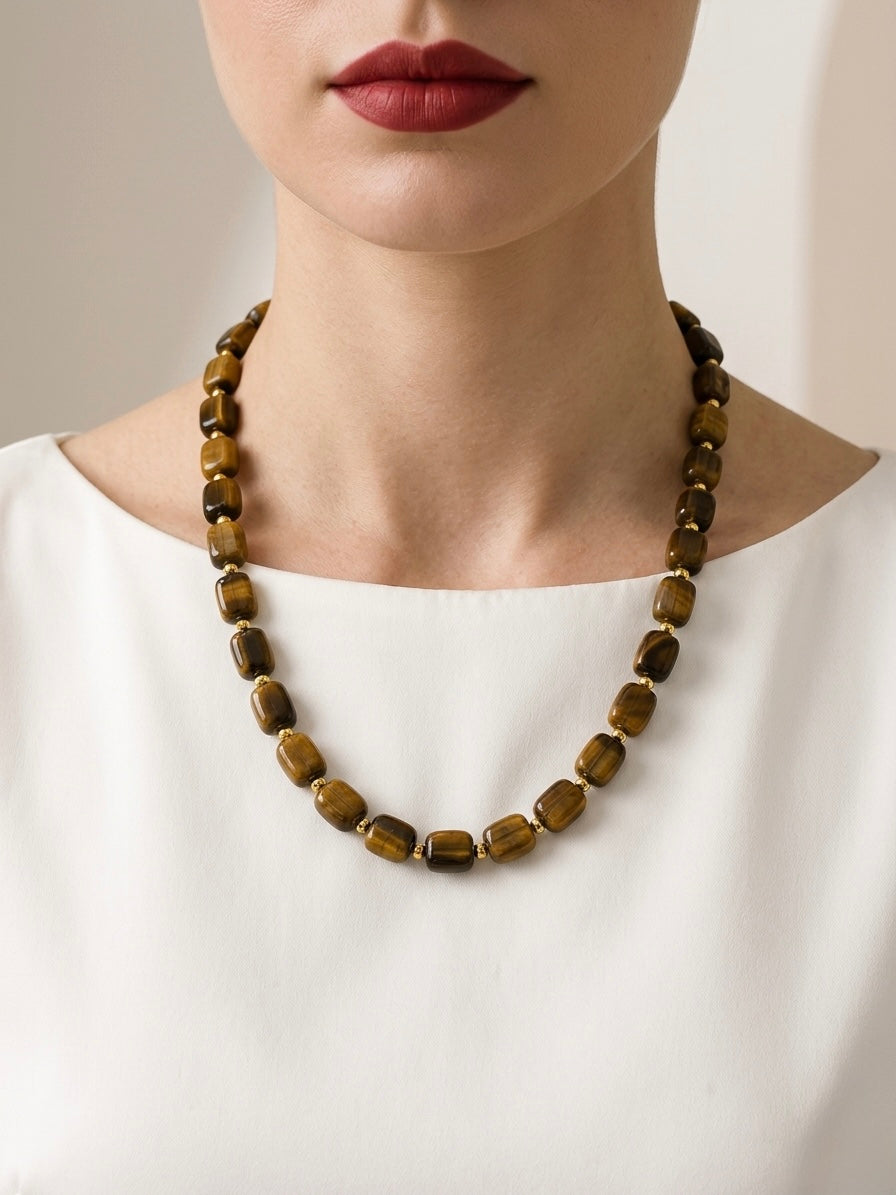 Necklace with brown beads worn by a person against a neutral background