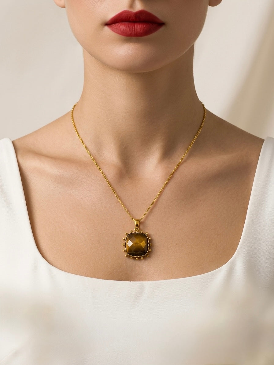 Gold necklace with a pendant worn by a person against a neutral background