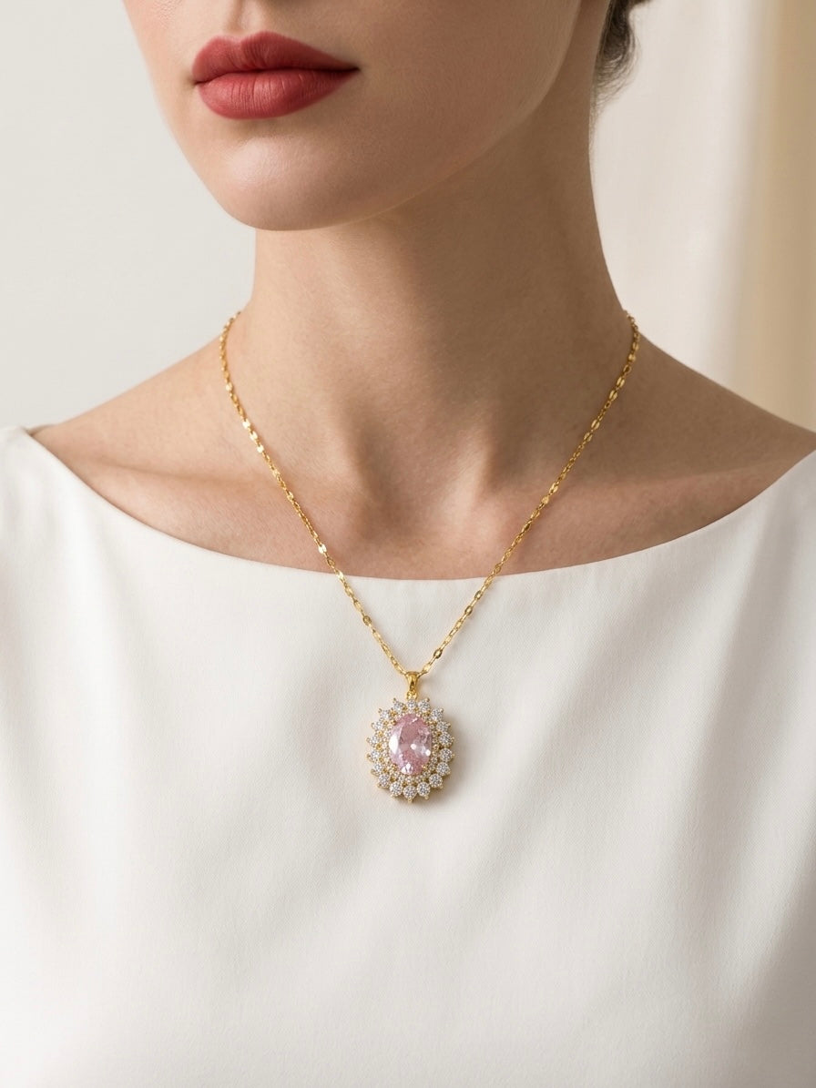 Necklace with a pink pendant worn by a person in a white top against a neutral background