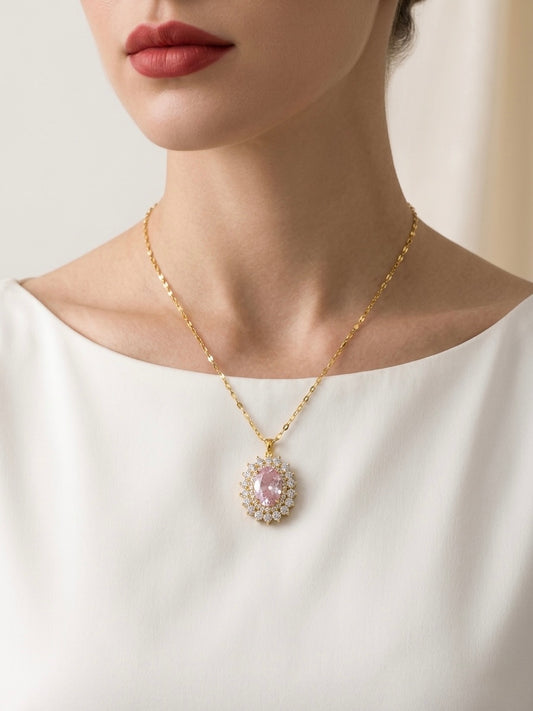 Necklace with a pink pendant worn by a person in a white top against a neutral background
