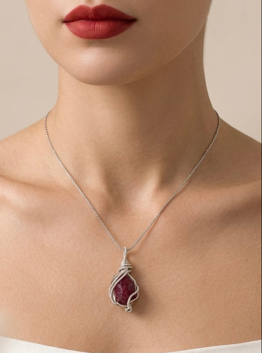 Necklace with a red gemstone pendant worn by a person against a neutral background