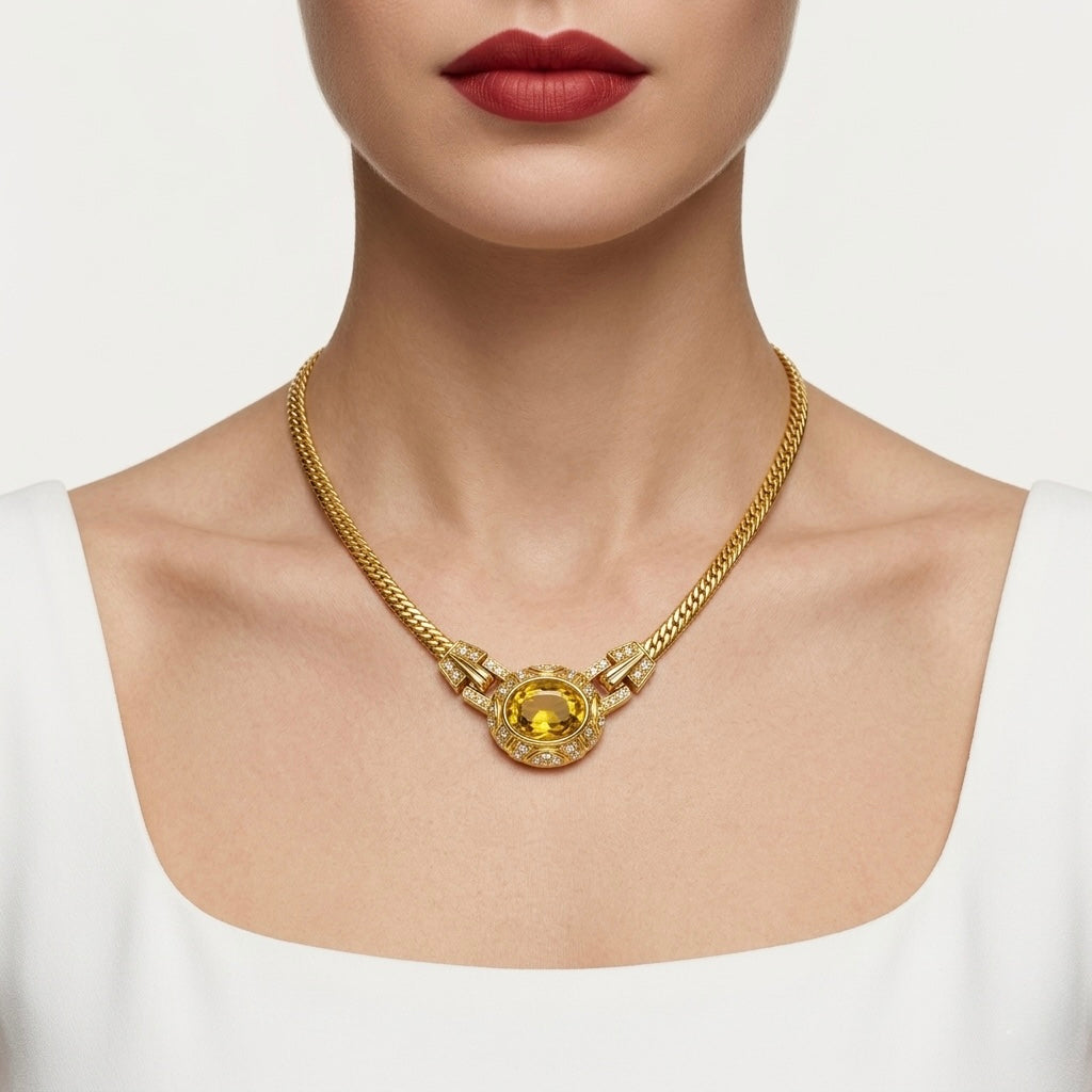 Gold necklace with a yellow gemstone worn by a model on a white background