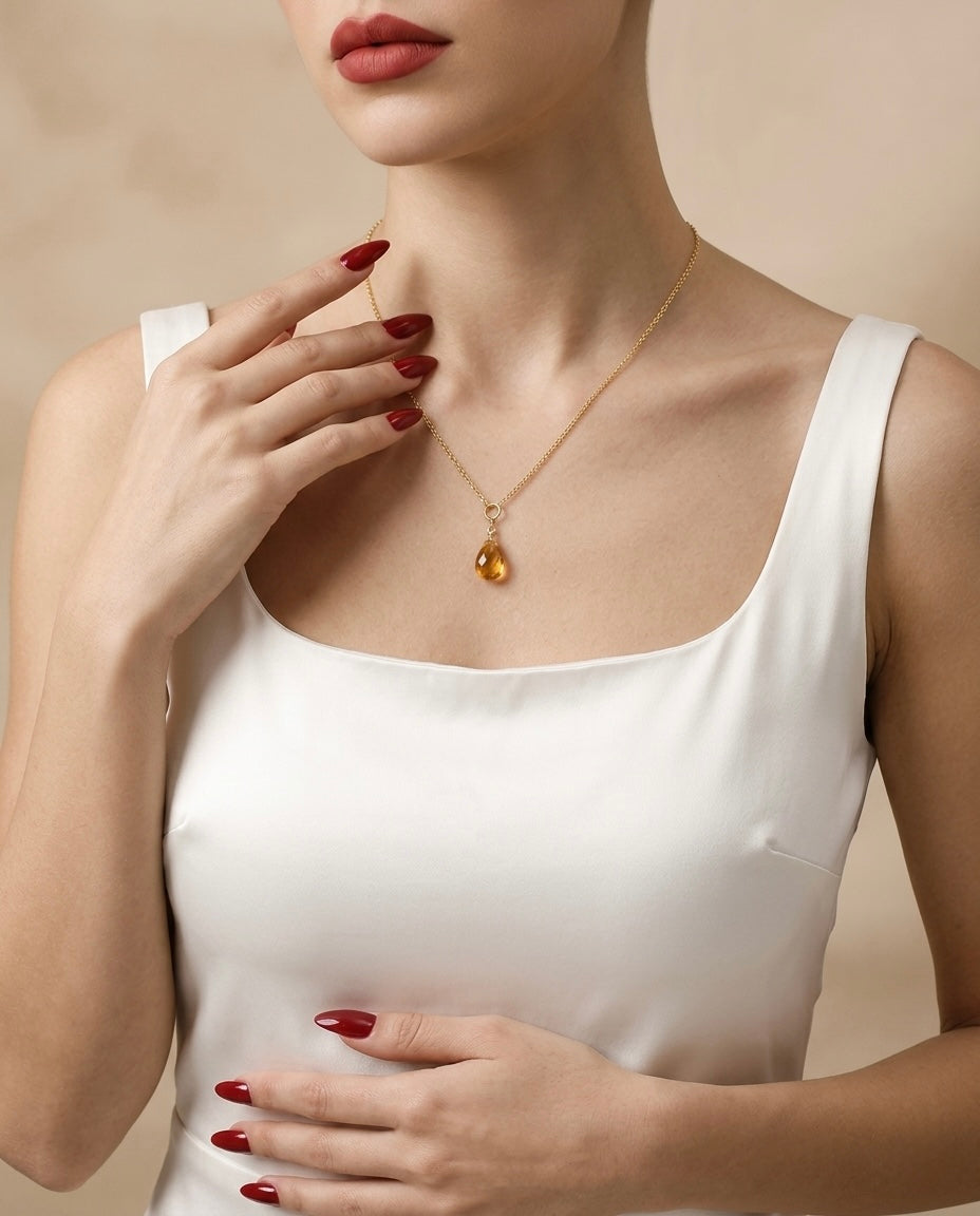 Woman wearing a gold necklace with a pendant against a beige background