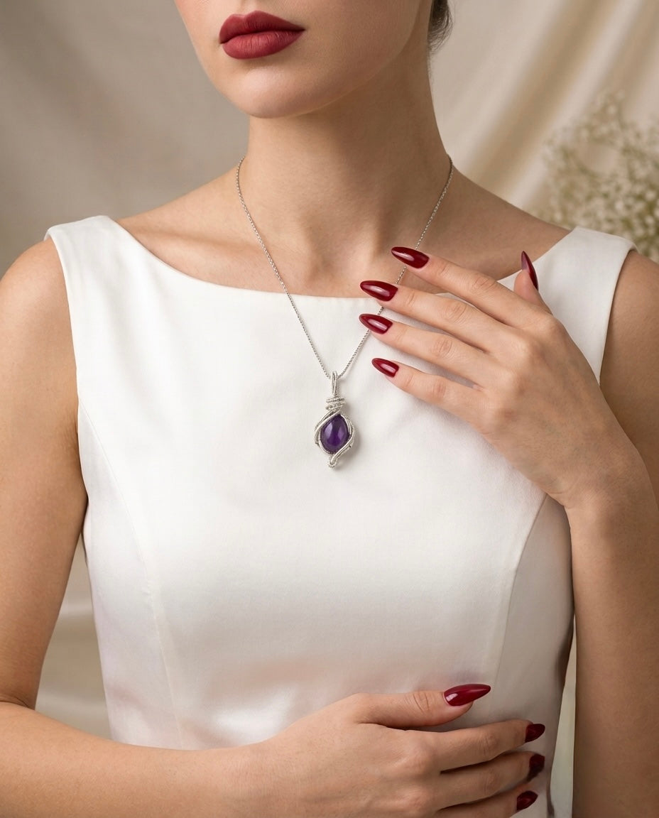 Woman wearing a necklace with an amethyst pendant, against a neutral background