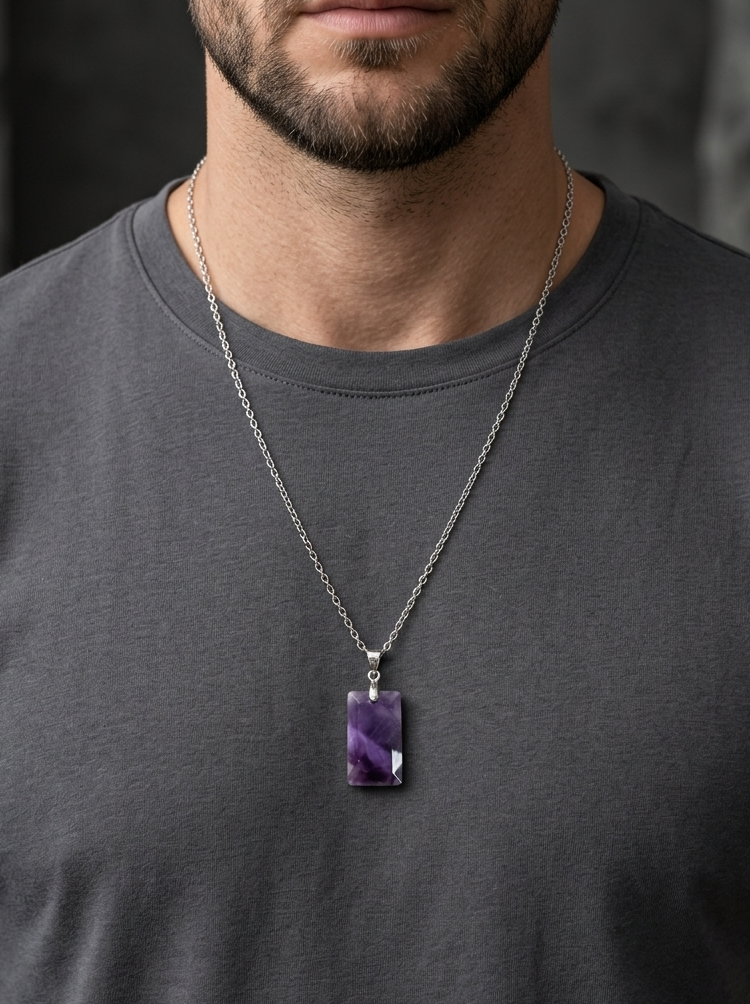 Man wearing a necklace with a purple pendant against a dark background