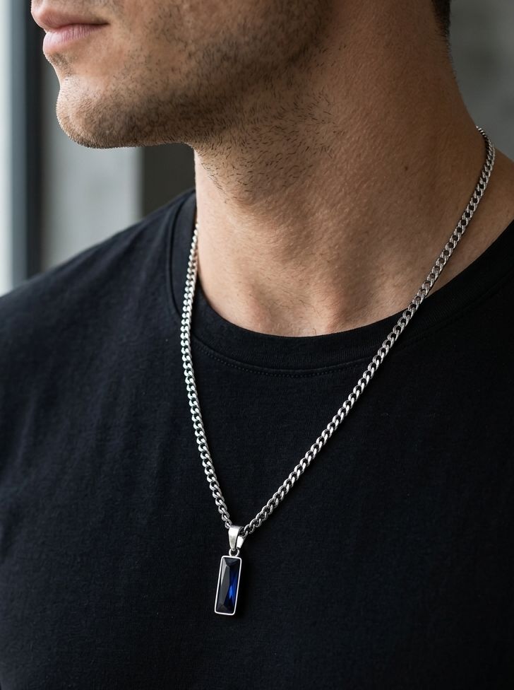 Man wearing a black t-shirt with a silver chain necklace featuring a pendant.