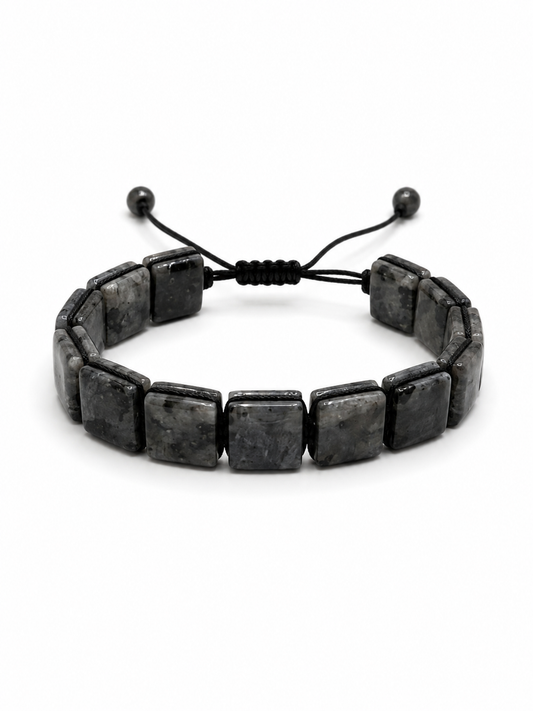 A black stone bracelet made of rectangular polished beads on a black adjustable cord, photographed on a clean white background.
