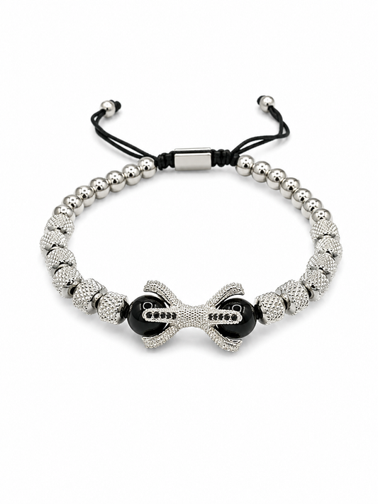 A silver beaded bracelet with a central bow-shaped charm, black beads, and a black adjustable cord closure, shown on a plain white background.