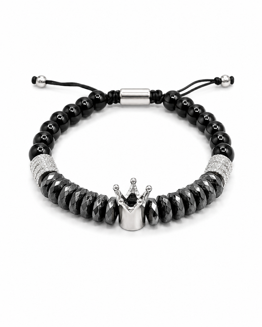 A black beaded bracelet with a silver crown charm, featuring faceted black beads, textured silver spacer rings, and an adjustable black cord closure with silver metal tips.