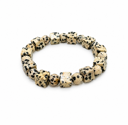 A beaded stretch bracelet made of polished Dalmatian-spotted stone cubes, displayed on a clean white background.
