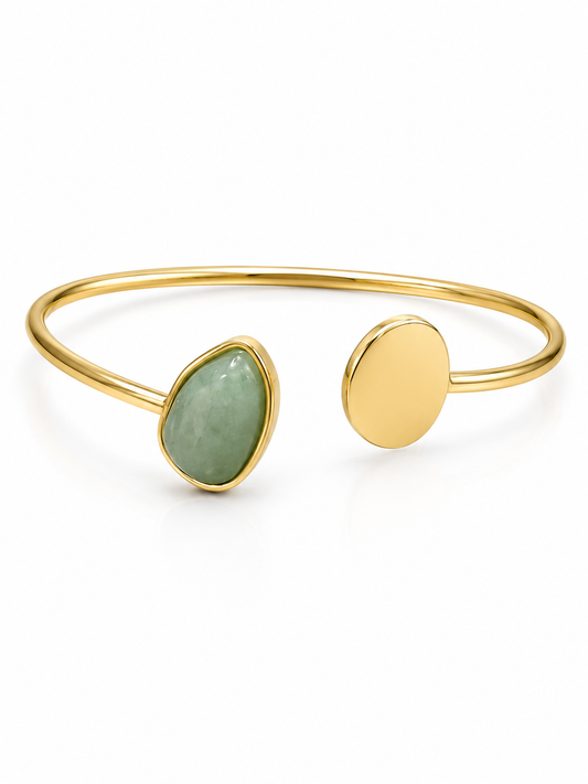 Gold open cuff bracelet with a teardrop-shaped light green stone and a flat oval gold disc, shown on a white background.