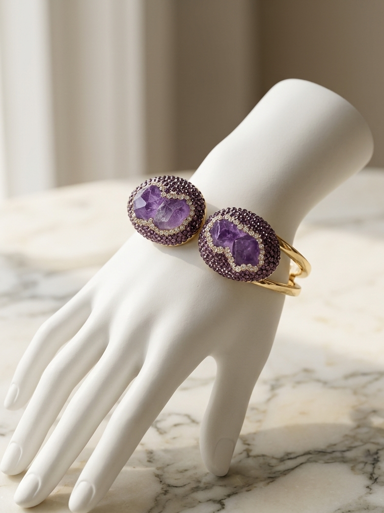 A pair of gold ring bands with oval purple agate dui gemstone inlays, displayed on a white ceramic mannequin hand over a marble surface.