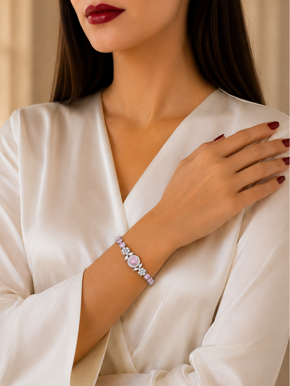 A woman wearing a white satin robe and dark red lipstick, showcasing a delicate pink and silver beaded bracelet on her wrist.