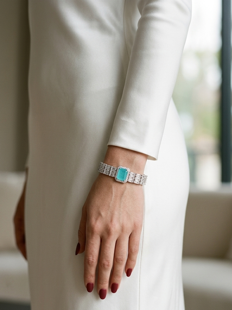 A close-up lifestyle shot of a woman wearing a silver-toned bracelet with a prominent turquoise rectangular stone, shown on her wrist as she wears a white dress.