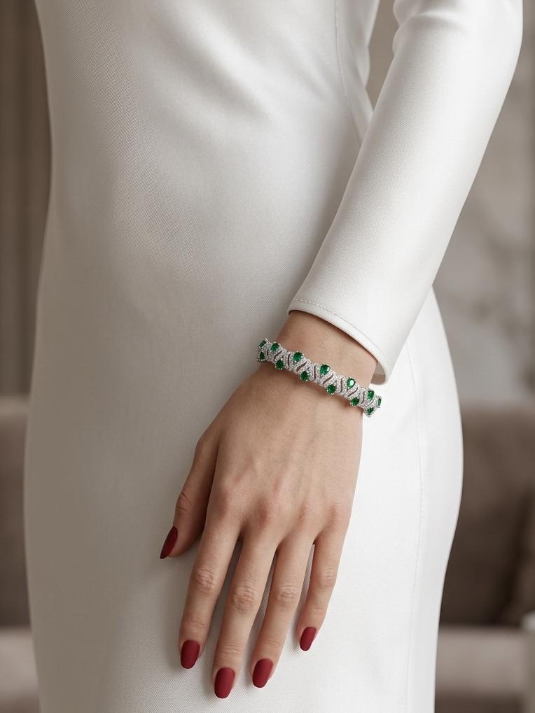 A close-up of a person wearing a delicate bracelet on their wrist, styled with a long-sleeved white dress and dark red manicured nails.
