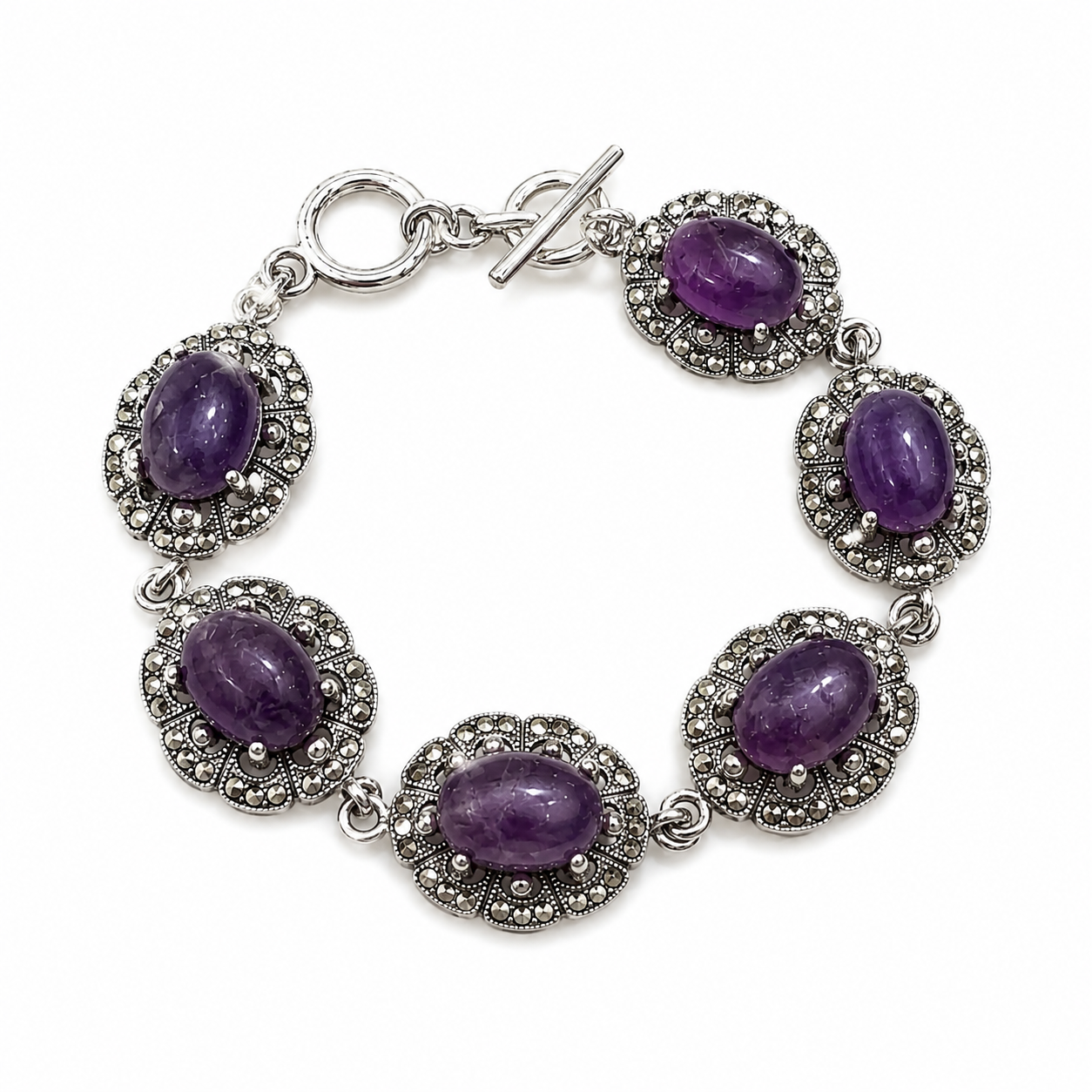 A silver-toned bracelet featuring five oval purple amethyst gemstones, each set within an ornate silver filigree frame, completed with a toggle clasp on a white background.