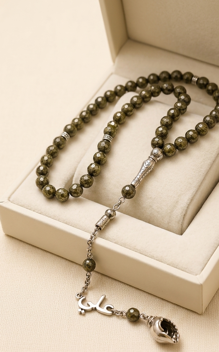 A beaded necklace with olive green and black marbled beads and silver-toned metal accents, displayed inside an open cream-colored jewelry box.
