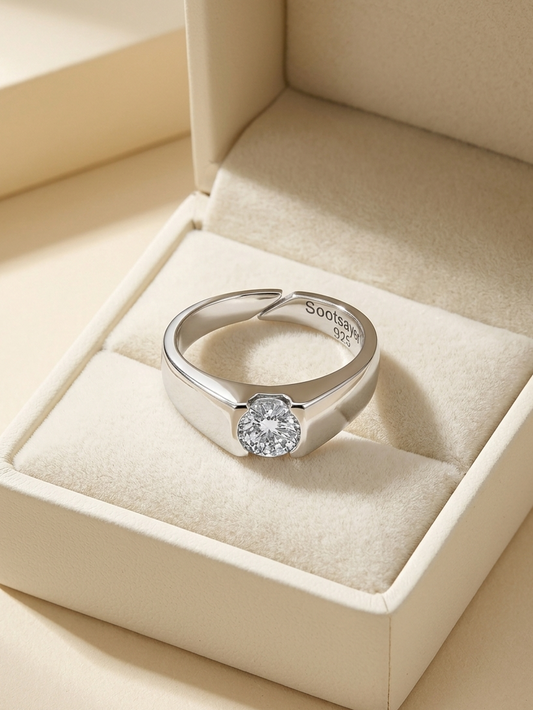 A silver ring with a round clear gemstone, displayed inside an open cream-colored jewelry box. The brand name 'SooShine' is engraved inside the band.