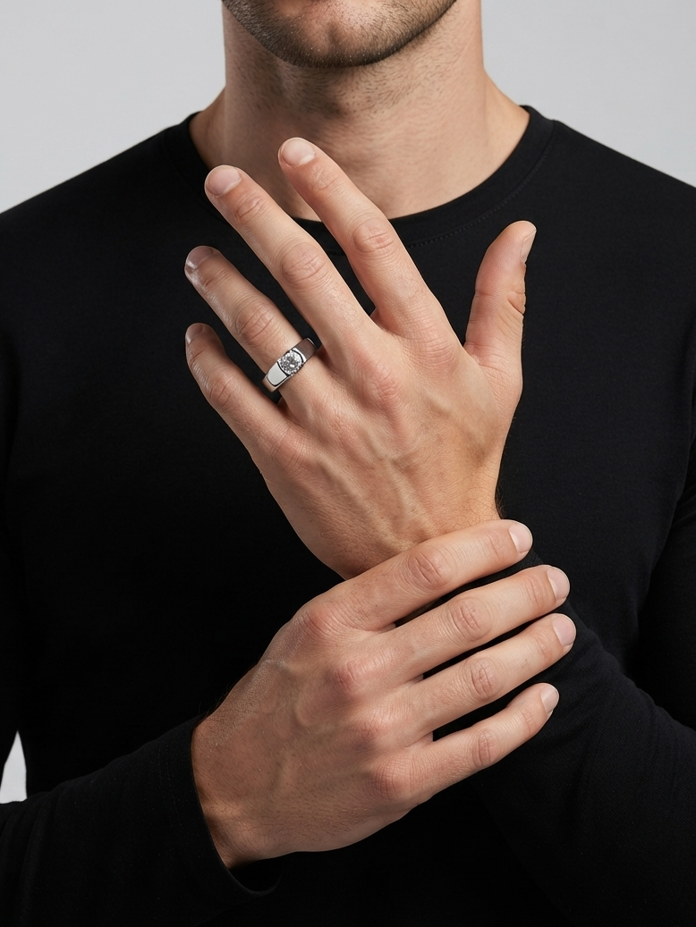 A close-up of a man wearing a black long-sleeve shirt, showcasing a silver band ring with a clear rectangular gemstone on his ring finger.