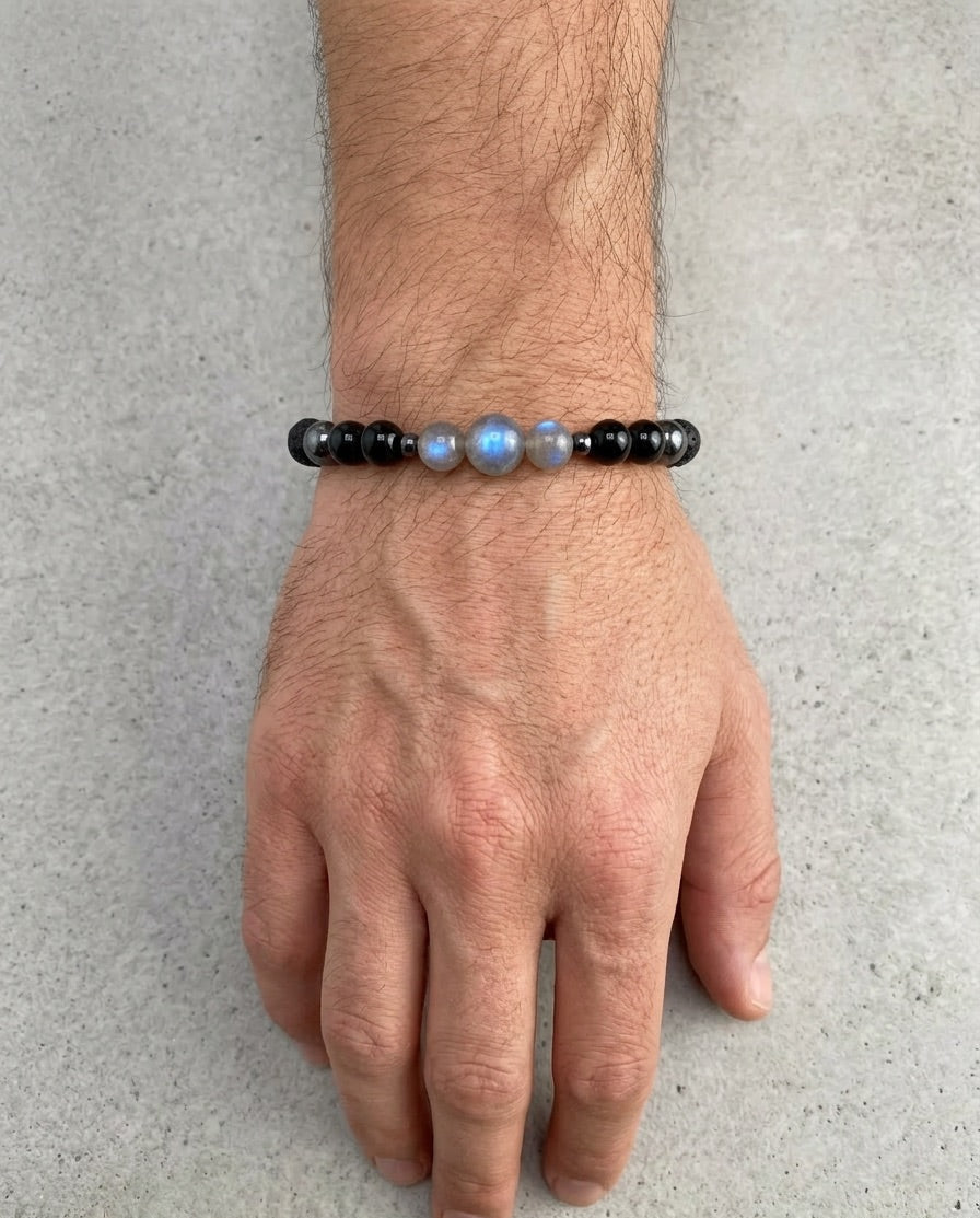 Hand wearing a beaded bracelet on a gray background
