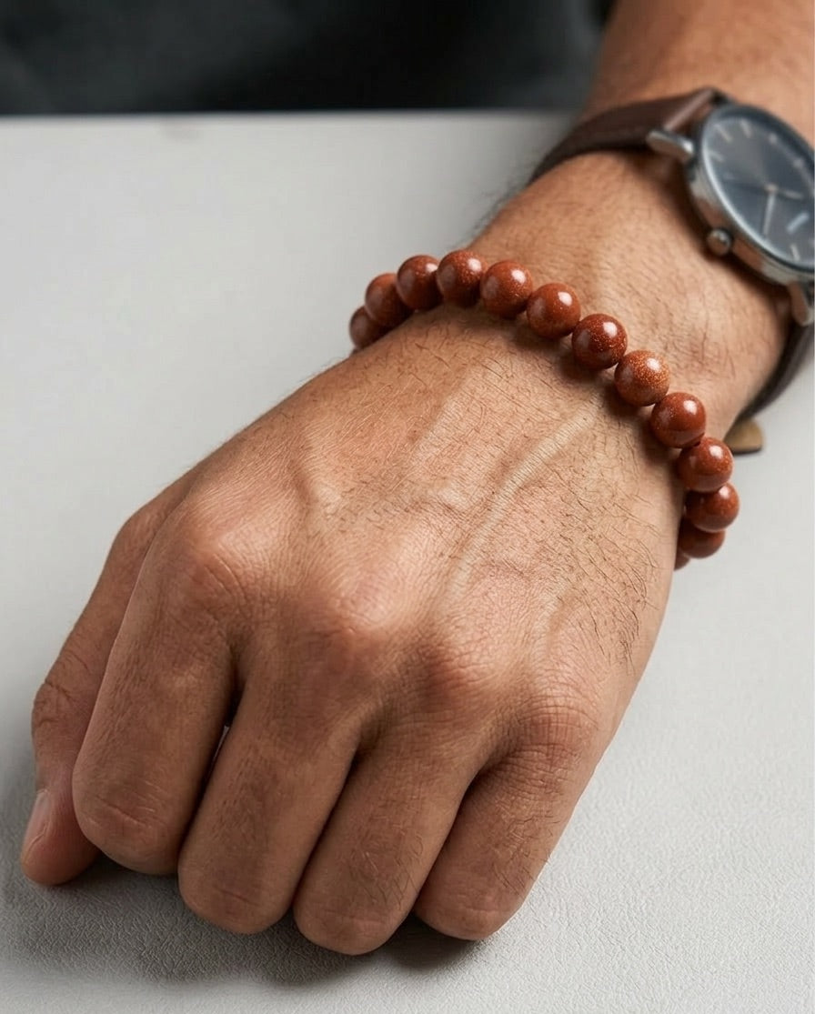 Hand wearing a red beaded bracelet on a light background