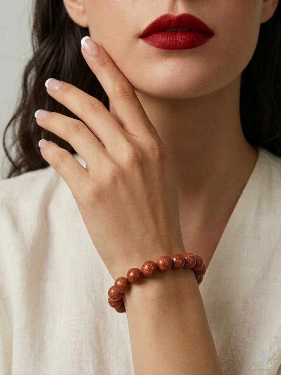 Close-up of a person wearing a red beaded bracelet on a neutral background