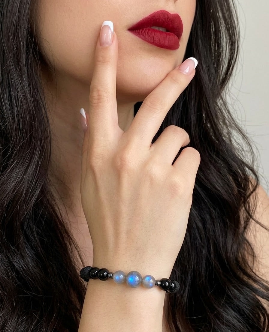Close-up of a person wearing a bracelet with dark beads, touching their lips.