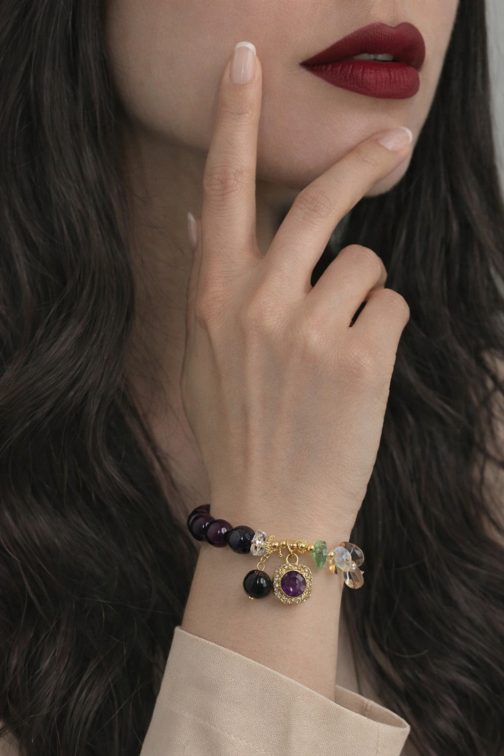 Close-up of a woman's hand wearing a bracelet with gemstones, against a blurred background.