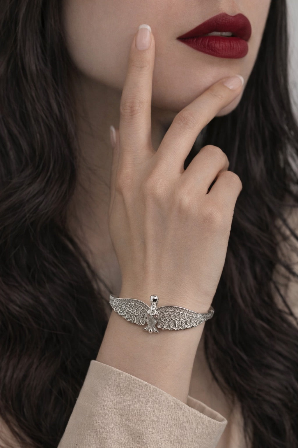 Close-up of a woman's hand wearing a silver bracelet with a delicate design, against a blurred background.