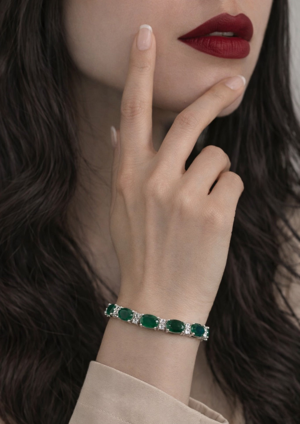 Close-up of a hand wearing an emerald bracelet with a blurred background