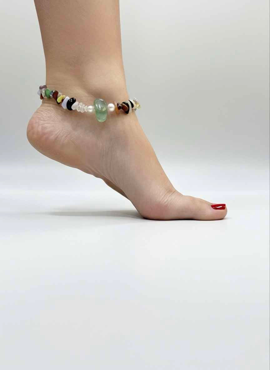 Ankle with a beaded anklet on a plain background