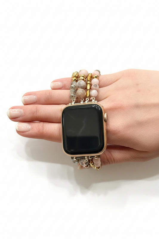 Hand holding a smartwatch with a decorative band on a white background