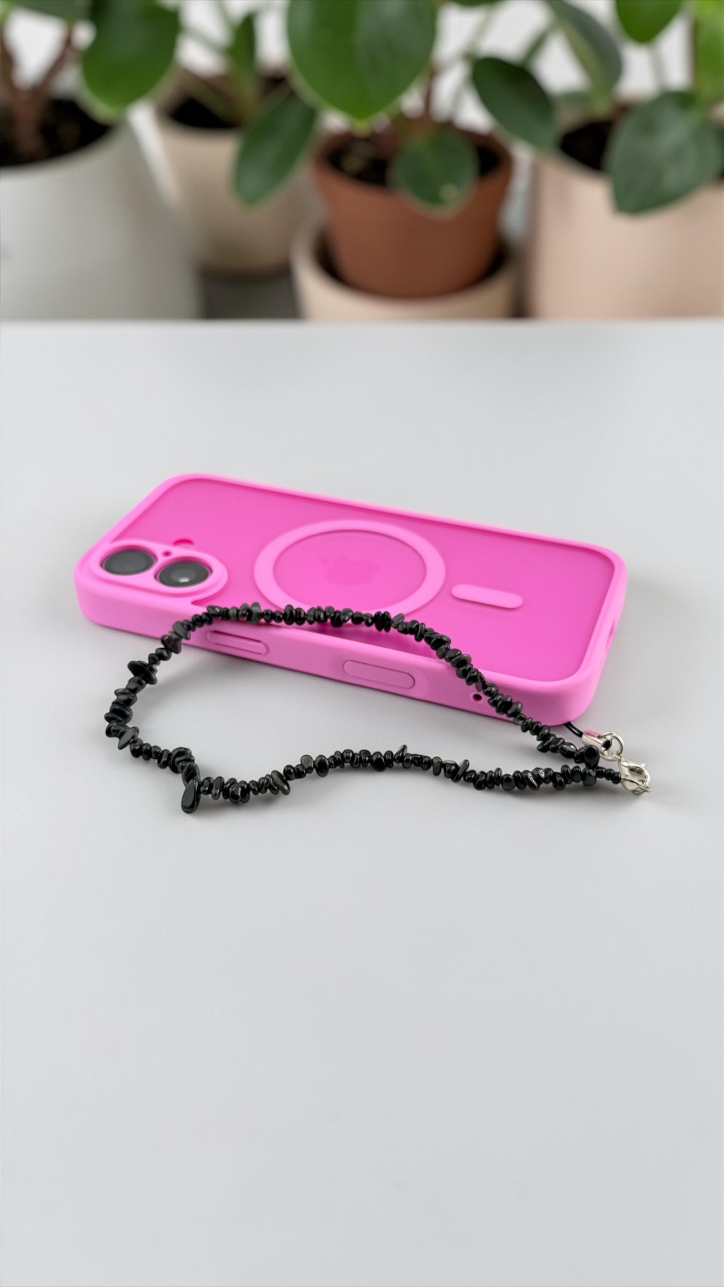 Pink phone case with black chain on a white surface