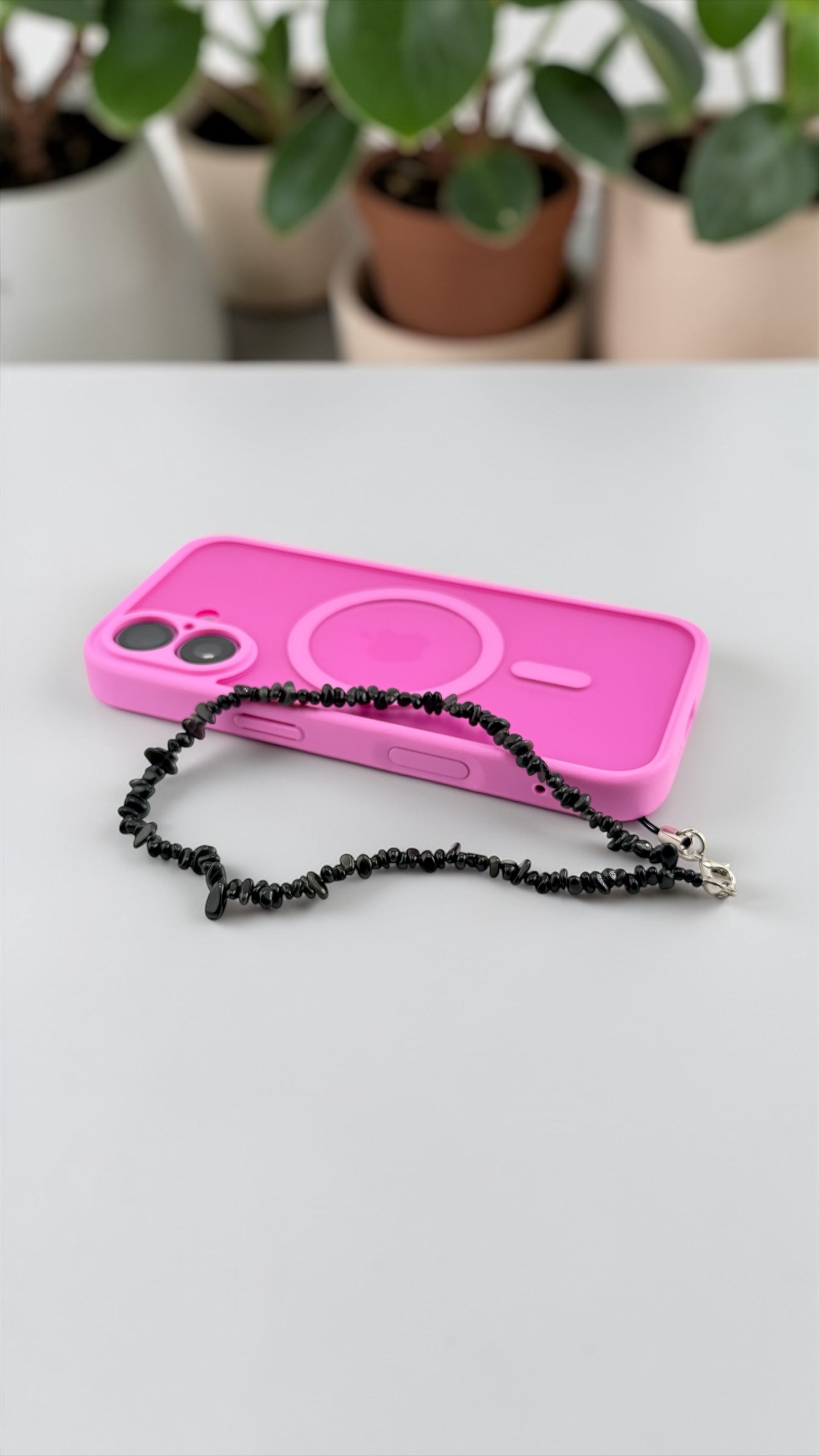 Pink phone case with black chain on a white surface