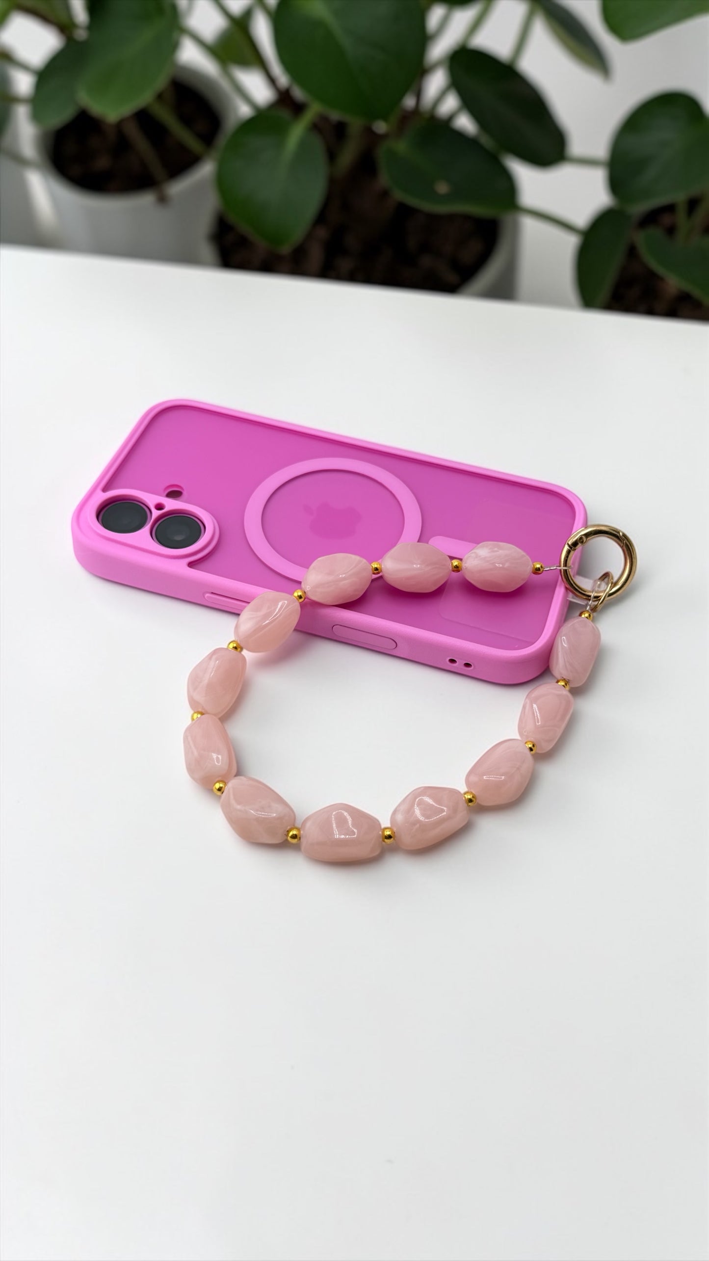 Pink phone case with a matching pink beaded keychain on a white surface.