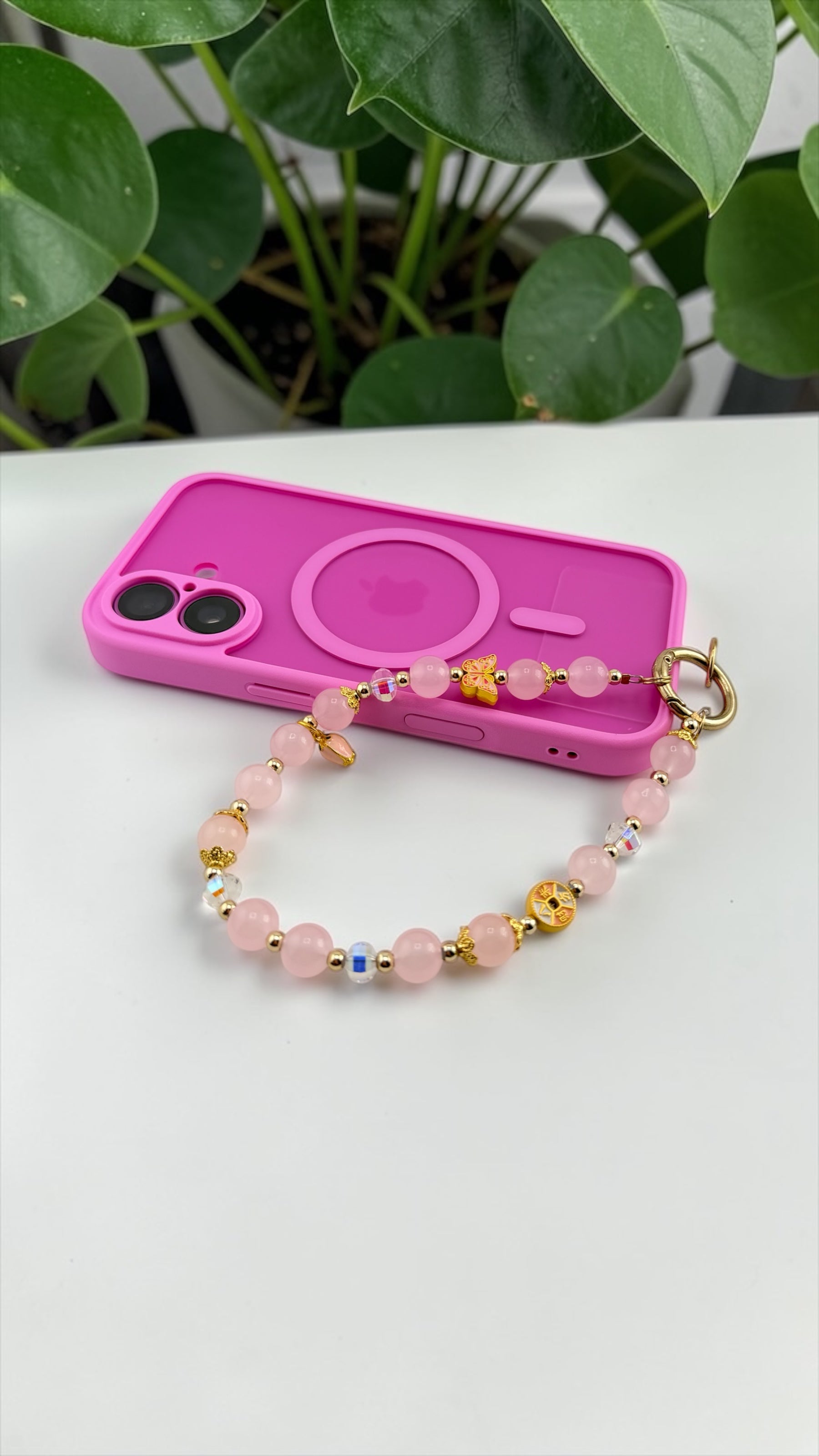 Pink phone case with a beaded bracelet on a white surface