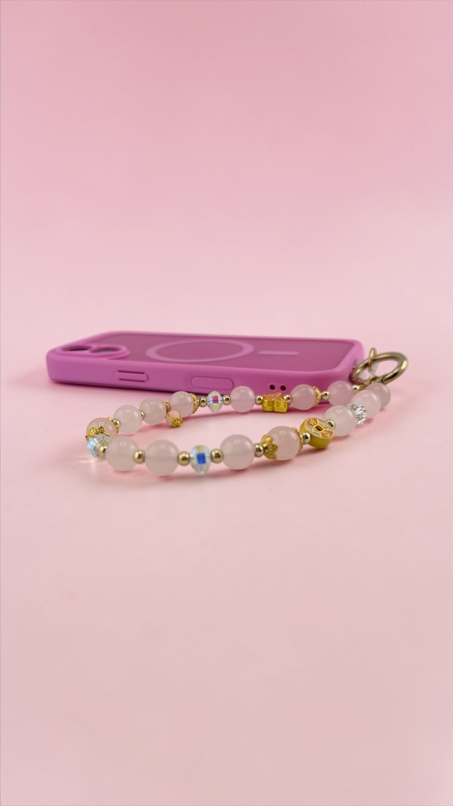 Pink phone case with a beaded keychain on a pink background