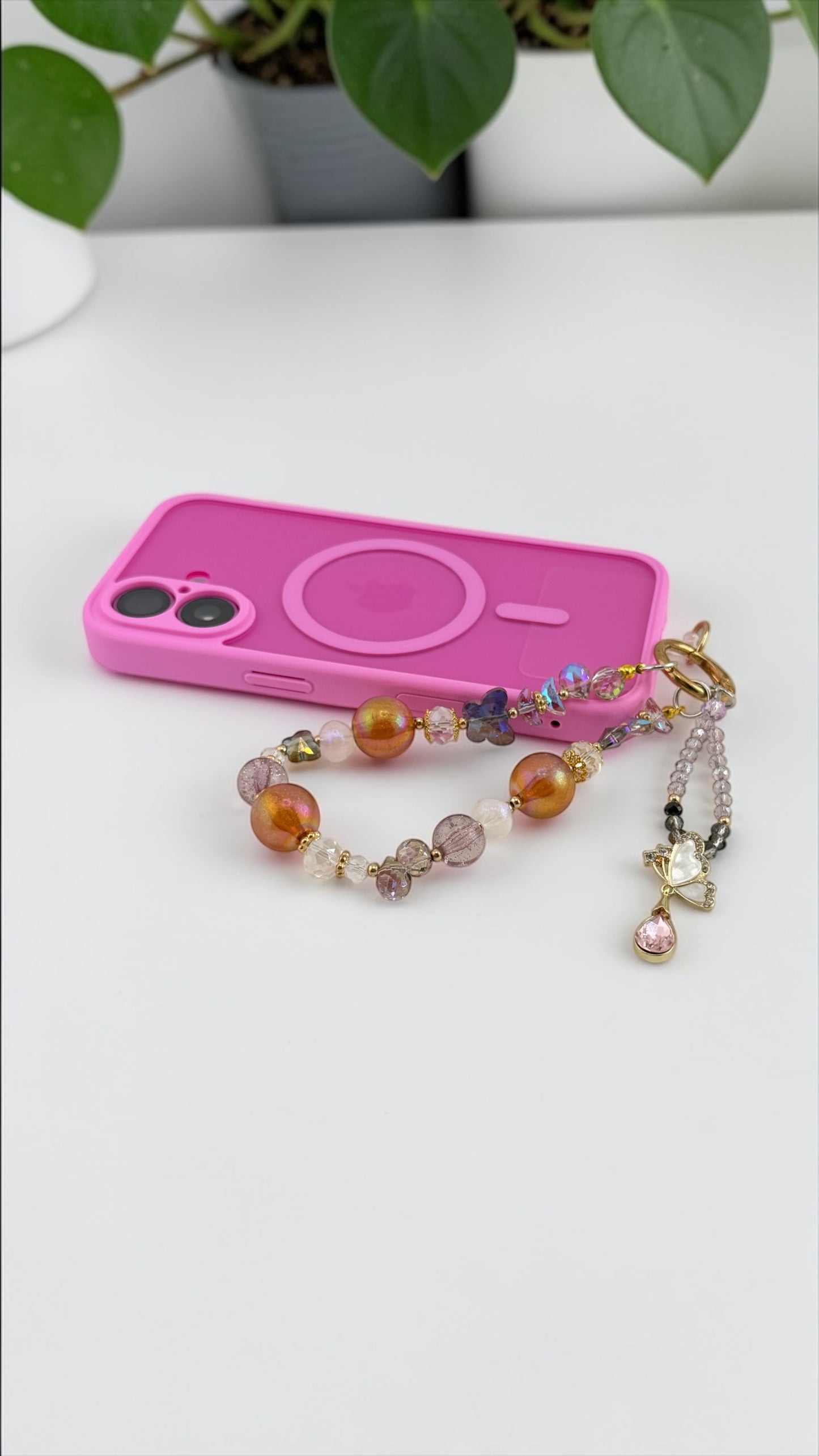 Pink phone case with a colorful beaded bracelet on a white surface